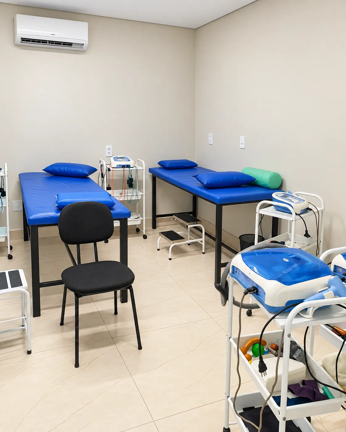 Sala de fisioterapia da clínica, com macas e equipamentos de eletroestimulação